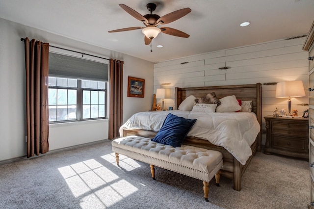 carpeted bedroom featuring ceiling fan and wood walls