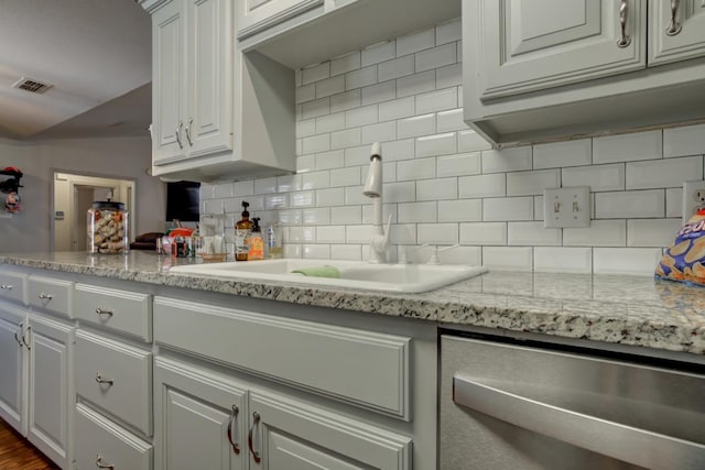 kitchen with sink, dishwasher, white cabinetry, light stone counters, and tasteful backsplash