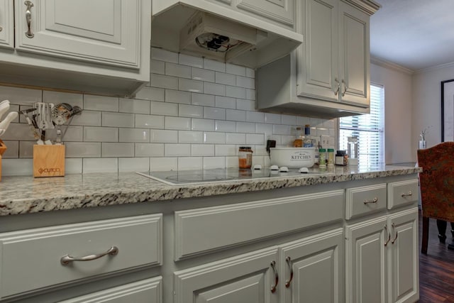 kitchen with crown molding, ventilation hood, light stone countertops, electric cooktop, and decorative backsplash