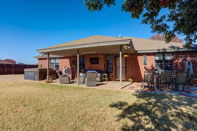 back of property with a hot tub, a lawn, and a patio area