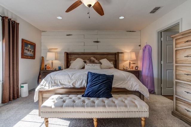 carpeted bedroom with ceiling fan and wood walls