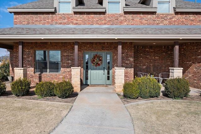 8405 E County Rd 6100, Idalou, TX 79329 - doorway to property featuring a shingled roof, brick siding, and covered porch