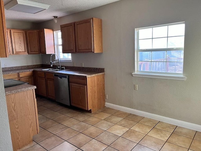 kitchen featuring sink, stainless steel dishwasher, a textured ceiling, and light tile patterned floors