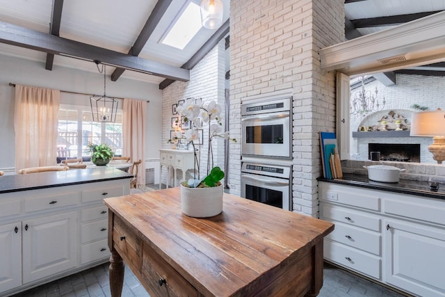 kitchen with white cabinetry, stainless steel double oven, hanging light fixtures, and a notable chandelier