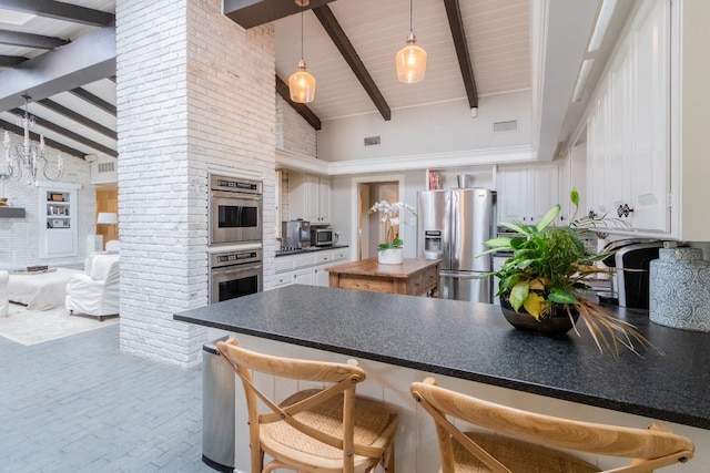 kitchen featuring pendant lighting, white cabinetry, high vaulted ceiling, stainless steel appliances, and beamed ceiling