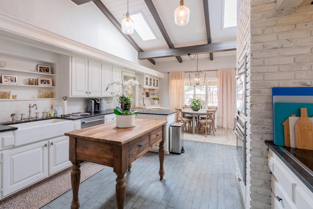 kitchen featuring sink, white cabinetry, decorative light fixtures, stainless steel dishwasher, and decorative backsplash