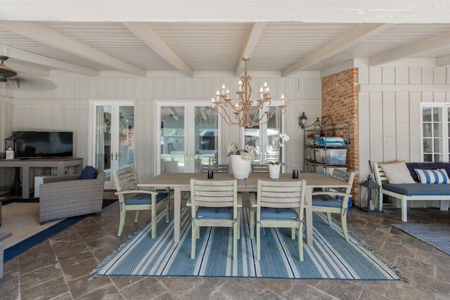 dining room featuring a notable chandelier, beam ceiling, and wooden walls