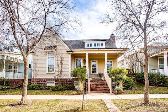 bungalow featuring covered porch and a front lawn