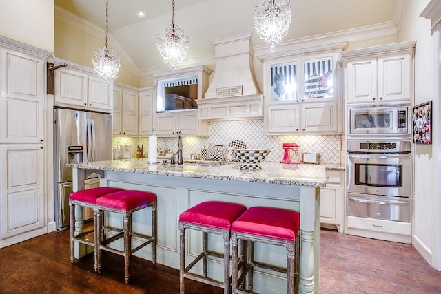 kitchen with a kitchen breakfast bar, an island with sink, and appliances with stainless steel finishes