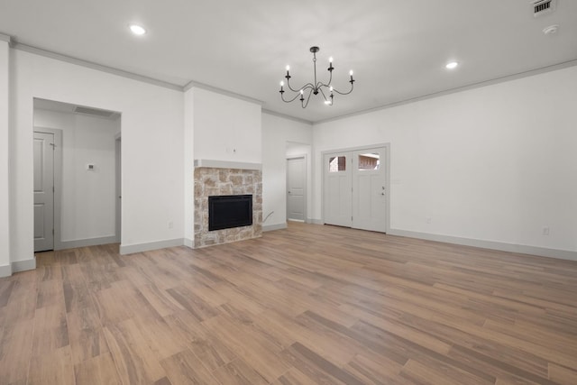 unfurnished living room featuring crown molding, a chandelier, a fireplace, and light hardwood / wood-style flooring