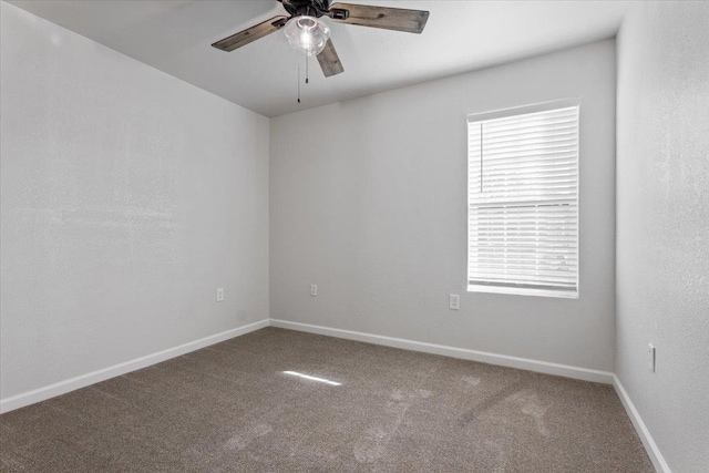 carpeted empty room with ceiling fan and baseboards