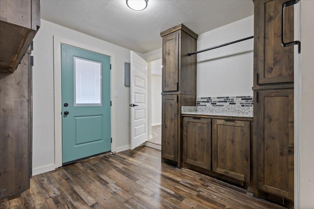 kitchen featuring a textured ceiling, dark wood finished floors, and dark brown cabinets