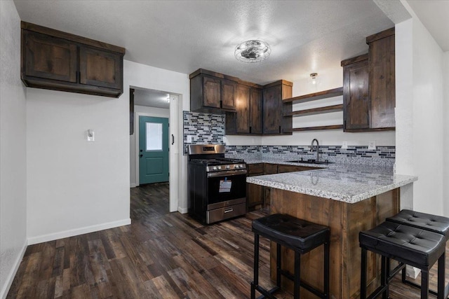 kitchen with a peninsula, a sink, dark brown cabinets, stainless steel gas stove, and open shelves