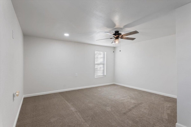 carpeted spare room with a ceiling fan and baseboards