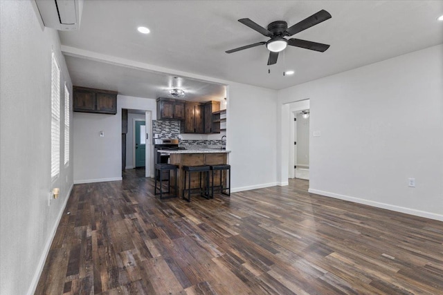 kitchen featuring a breakfast bar, dark wood-style flooring, light countertops, decorative backsplash, and dark brown cabinetry