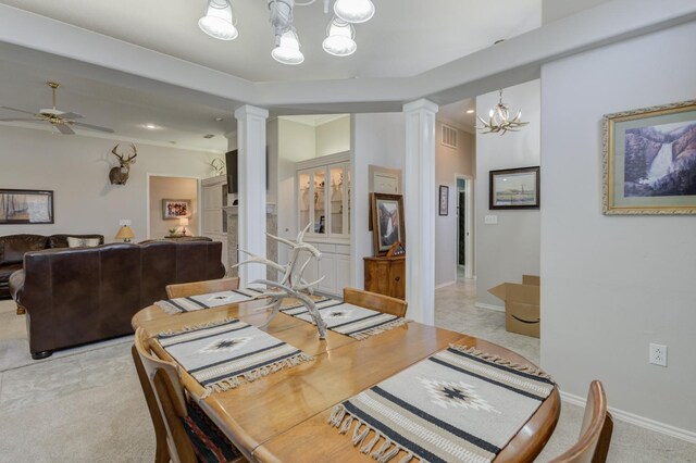 carpeted dining room with ornate columns and ceiling fan with notable chandelier