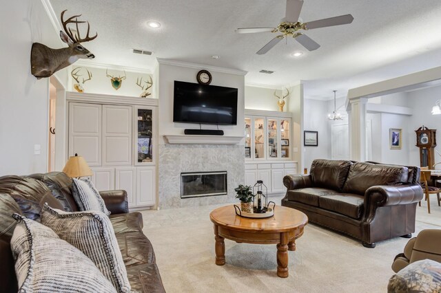 carpeted living room featuring ornate columns, ornamental molding, a textured ceiling, and a tile fireplace