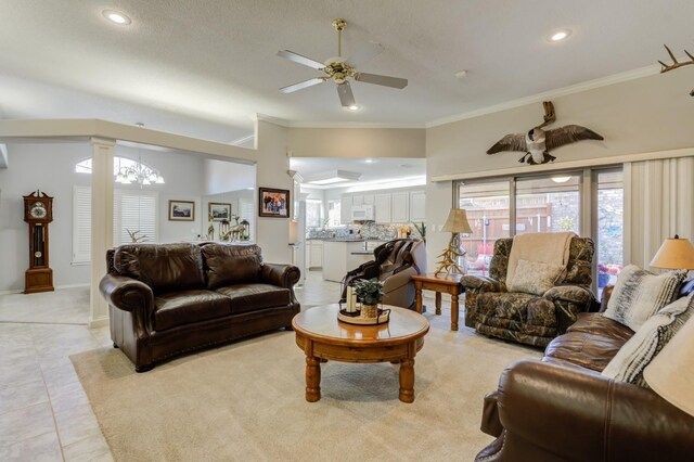 tiled living room featuring ornamental molding, ceiling fan with notable chandelier, and ornate columns