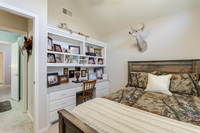 tiled bedroom featuring vaulted ceiling and built in desk