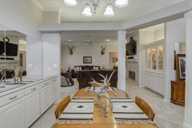 carpeted dining room featuring crown molding, ceiling fan, a fireplace, and decorative columns