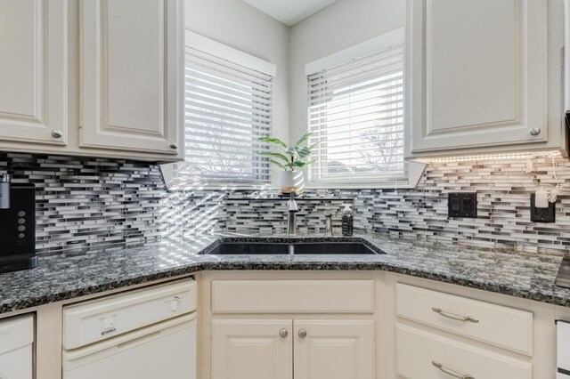 kitchen with dishwasher, sink, white cabinets, and dark stone counters