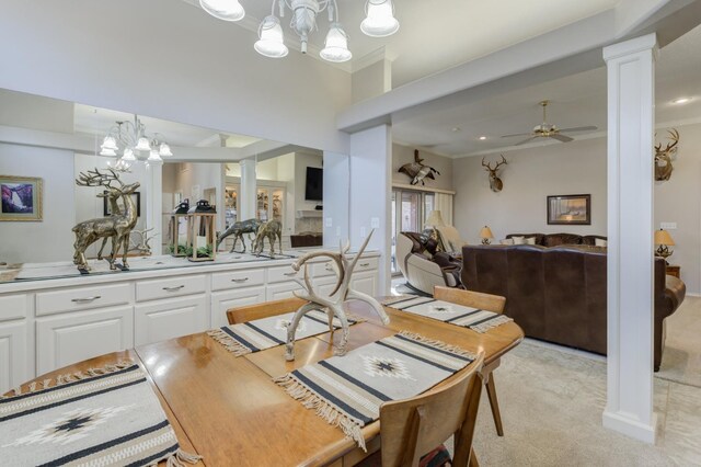 carpeted dining space featuring ornate columns, ornamental molding, and ceiling fan with notable chandelier