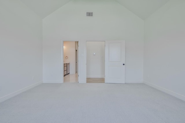 unfurnished bedroom featuring connected bathroom, light carpet, and high vaulted ceiling