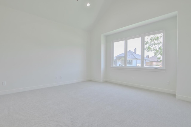 spare room featuring light colored carpet and lofted ceiling