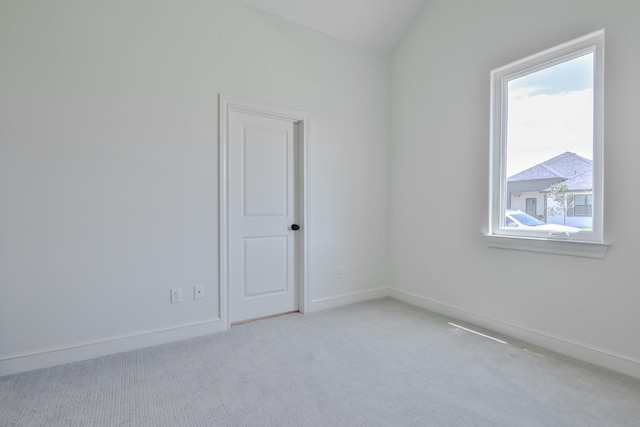 carpeted empty room featuring vaulted ceiling