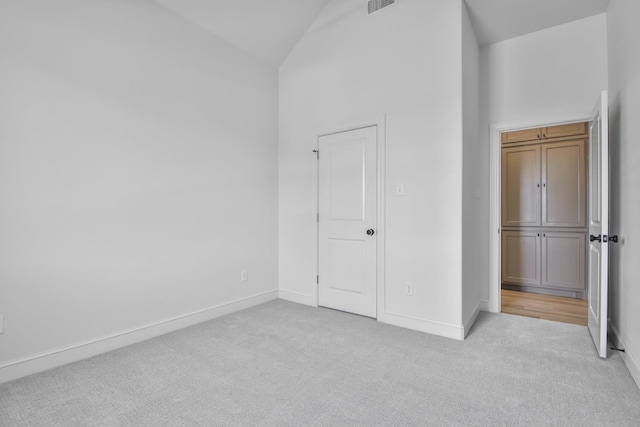 unfurnished bedroom featuring light colored carpet and high vaulted ceiling