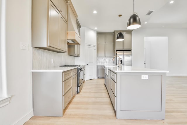 kitchen featuring premium range hood, pendant lighting, tasteful backsplash, stainless steel appliances, and a center island with sink