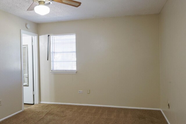 spare room featuring ceiling fan, light carpet, and a textured ceiling