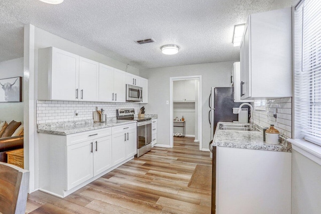 5408 22nd St, Lubbock, TX 79407 - kitchen with white cabinets, visible vents, appliances with stainless steel finishes, a sink, and light wood-style floors