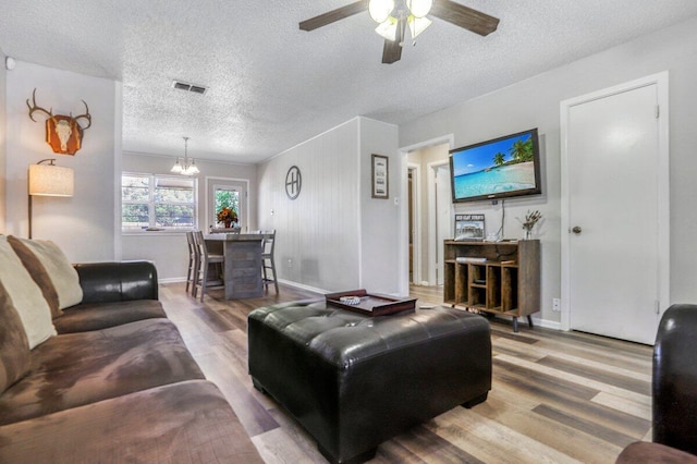 5408 22nd St, Lubbock, TX 79407 - living room featuring a textured ceiling, visible vents, ceiling fan with notable chandelier, and wood finished floors