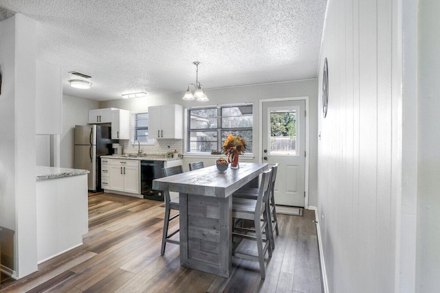 5408 22nd St, Lubbock, TX 79407 - kitchen featuring wood finished floors, black dishwasher, a sink, an inviting chandelier, and freestanding refrigerator