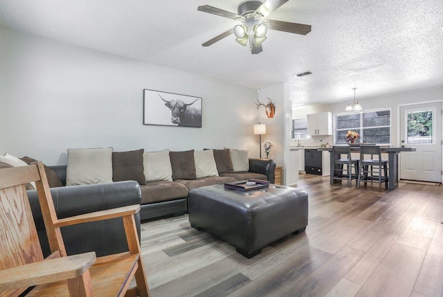 5408 22nd St, Lubbock, TX 79407 - living room featuring a textured ceiling, visible vents, light wood-style flooring, and a ceiling fan