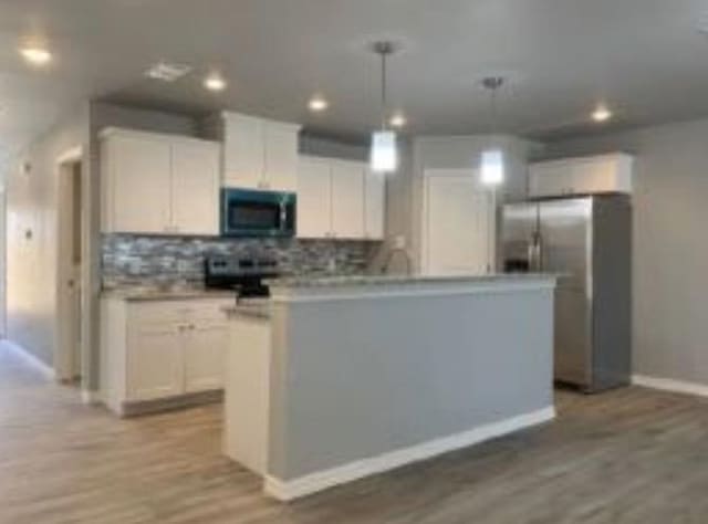 kitchen featuring white cabinetry, stainless steel refrigerator with ice dispenser, a center island, and pendant lighting