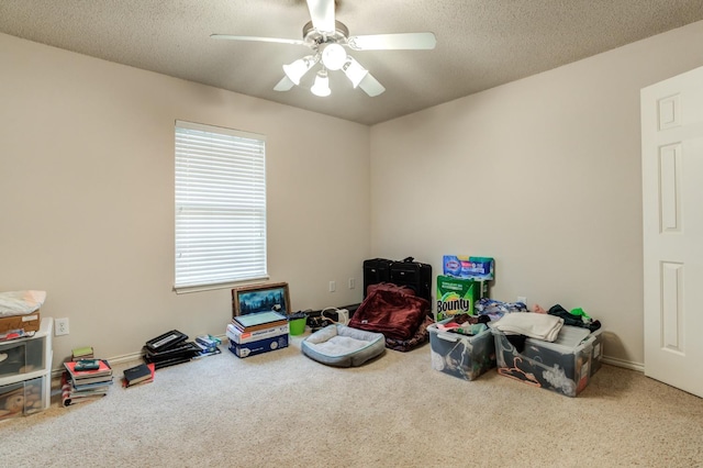 playroom featuring ceiling fan, carpet, and a textured ceiling