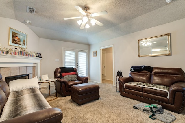 carpeted living room featuring lofted ceiling, a textured ceiling, a tile fireplace, and ceiling fan