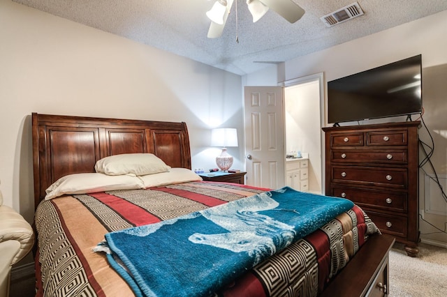 bedroom with ceiling fan, light colored carpet, and a textured ceiling