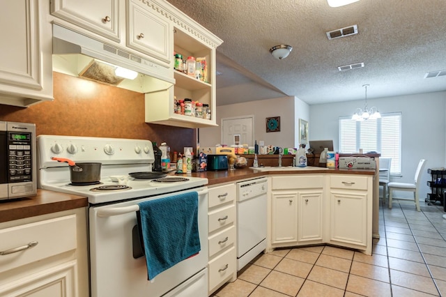 kitchen with light tile patterned floors, white appliances, an inviting chandelier, decorative light fixtures, and kitchen peninsula