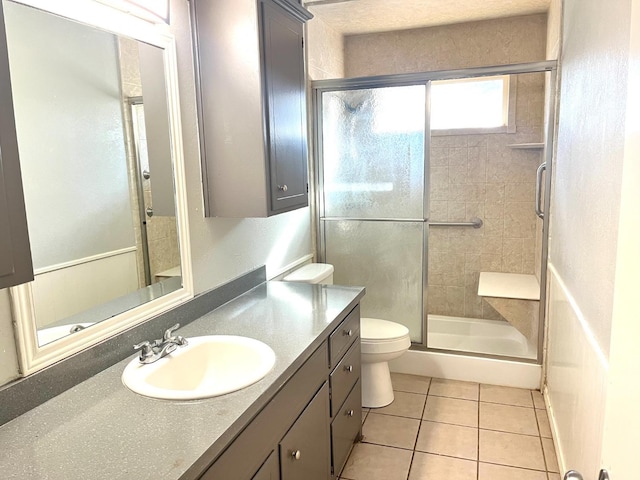 bathroom with vanity, toilet, a shower with shower door, and tile patterned flooring