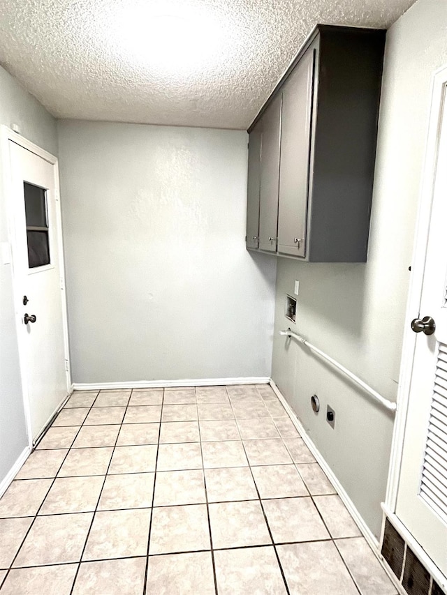 laundry area with light tile patterned floors, hookup for a washing machine, cabinets, and a textured ceiling