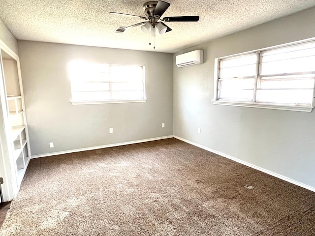 carpeted spare room featuring ceiling fan, a healthy amount of sunlight, a wall unit AC, and a textured ceiling