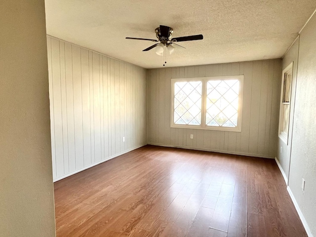 unfurnished room with hardwood / wood-style flooring, ceiling fan, and a textured ceiling