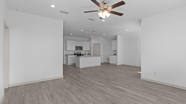 unfurnished living room featuring a ceiling fan, a sink, visible vents, and light wood-style flooring