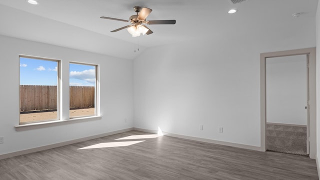 empty room with vaulted ceiling, ceiling fan, baseboards, and wood finished floors
