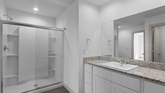 bathroom with recessed lighting, wood finished floors, vanity, and a stall shower