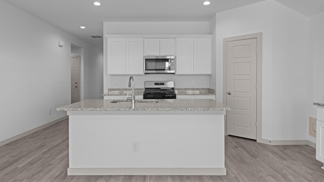 kitchen featuring a sink, a kitchen island with sink, appliances with stainless steel finishes, white cabinetry, and visible vents