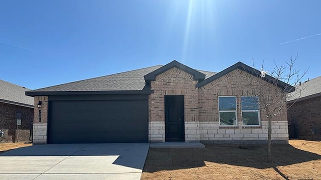 single story home with driveway, stone siding, a garage, brick siding, and a shingled roof